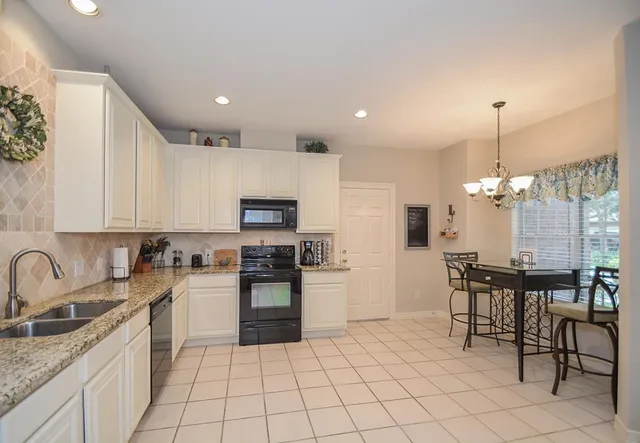 a kitchen with kitchen island granite countertop a sink counter top space appliances and cabinets