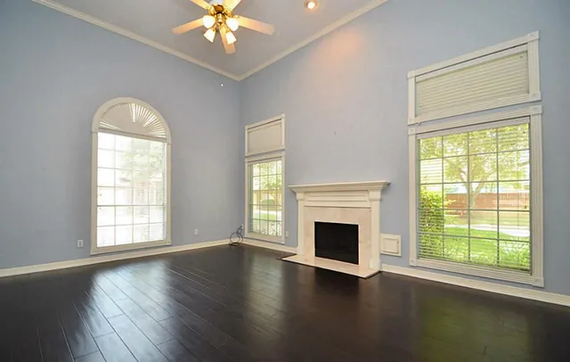 a view of an empty room with wooden floor and a window