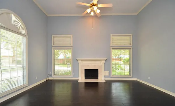 an empty room with wooden floor chandelier and windows