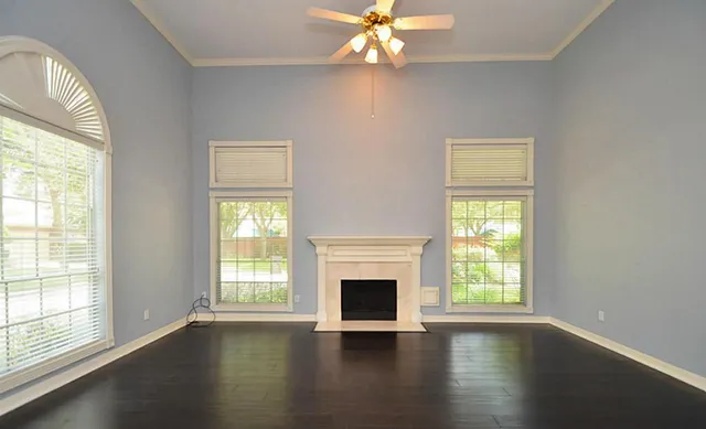 an empty room with wooden floor chandelier and windows