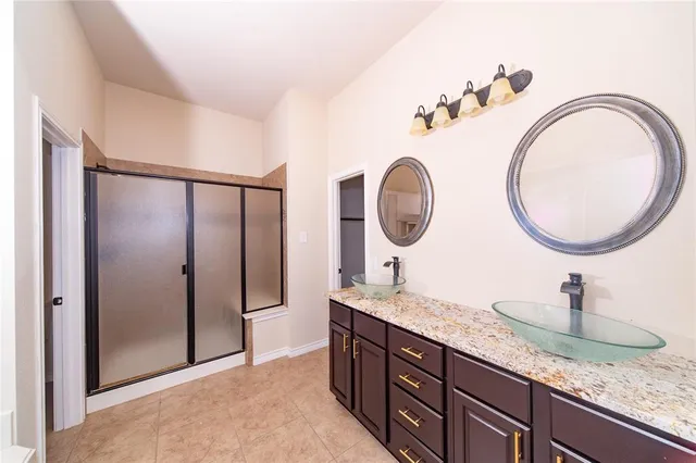 a bathroom with a granite countertop double vanity sink and a mirror