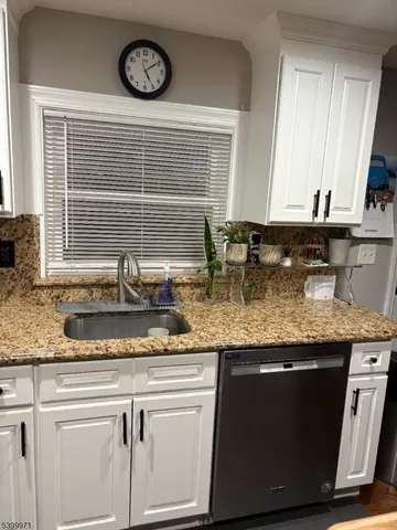 a kitchen with granite countertop a sink a stove and cabinets