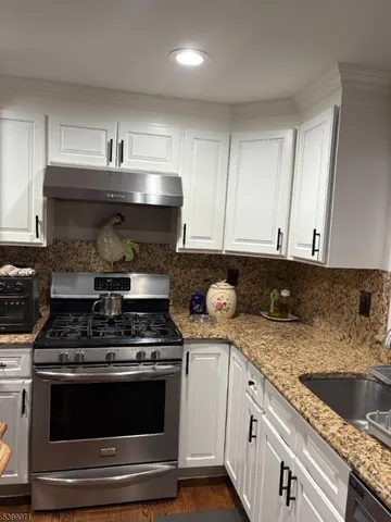 a kitchen with stainless steel appliances granite countertop a sink stove and cabinets