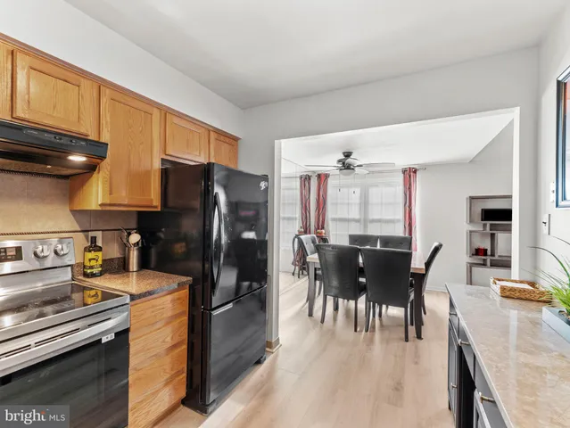 a kitchen with granite countertop a refrigerator dining table and chairs