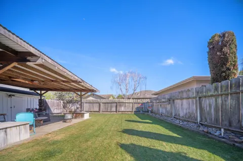 a view of a backyard with wooden fence and a large tree