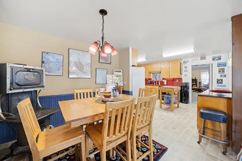 a view of a dining room and livingroom with furniture wooden floor a rug a painting and a chandelier