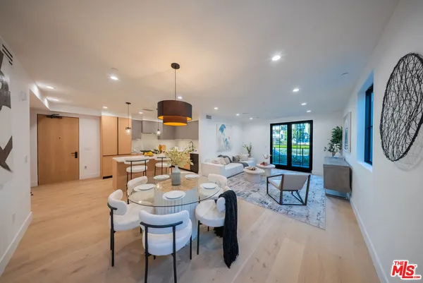 a view of a dining room and livingroom with furniture wooden floor a rug a painting and a chandelier