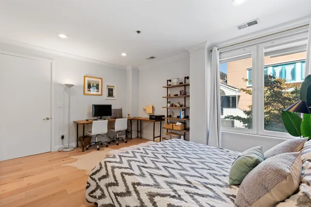 a bedroom with a bed a table and a large window