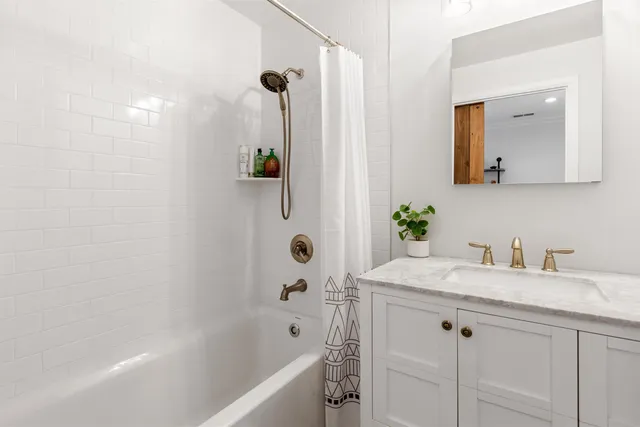 a bathroom with a granite countertop sink a mirror a vanity and bathtub