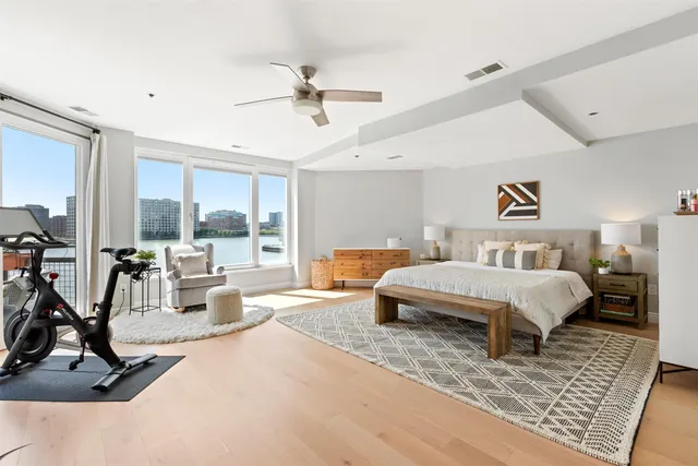 a spacious bedroom with a large bed a chandelier and windows