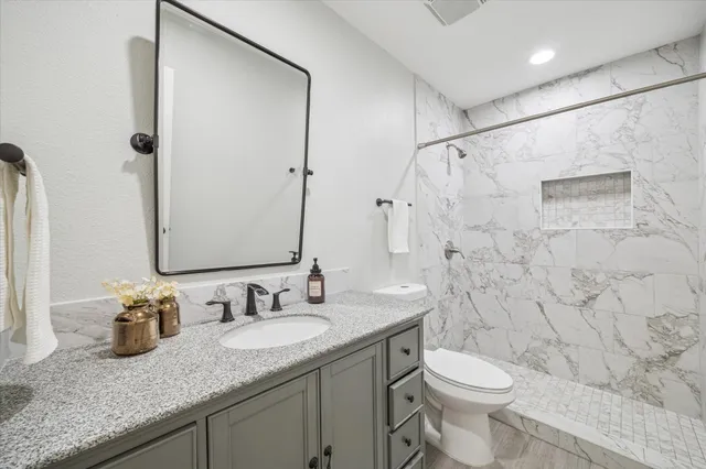 a bathroom with a granite countertop sink a toilet and a shower