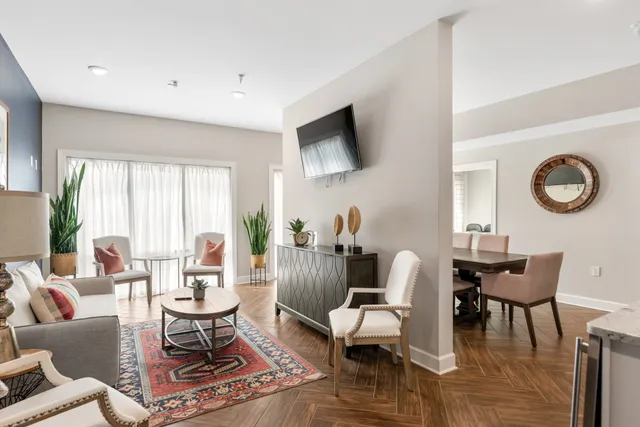 a living room with furniture a rug a window and a flat screen tv