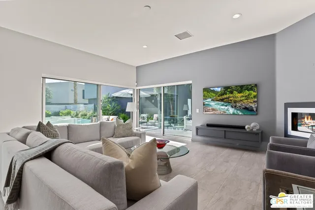 a living room with furniture a flat screen tv and a large window