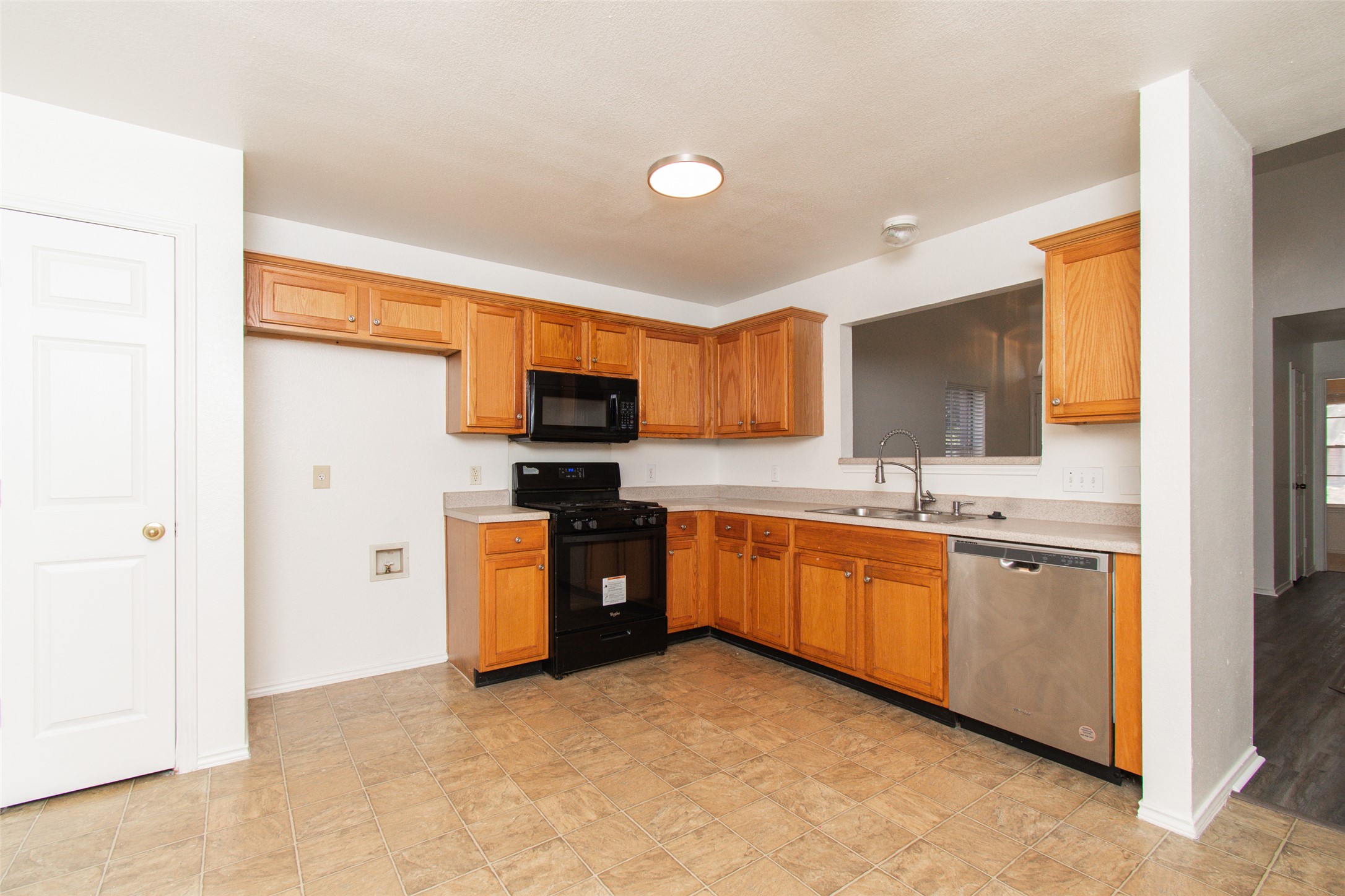 1436 Roxanne's Run Pflugerville, TX 78660 - Photo 5 of 24 Warm wood cabinetry and tile flooring ground this functional, open kitchen layout.
