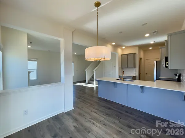 a view of a kitchen with kitchen island a sink wooden floor and a living room view