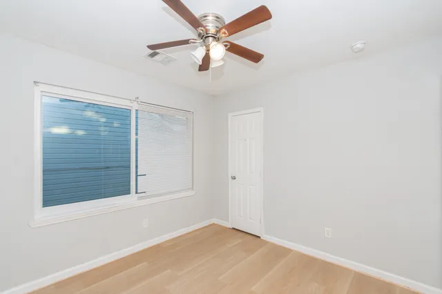 an empty room with windows and fan
