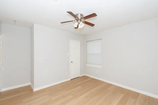 a view of an empty room with window and a ceiling fan