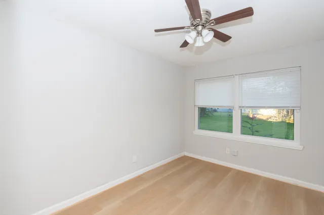 an empty room with a window and a fan