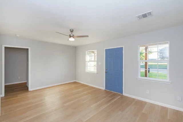 a view of an empty room with wooden floor and a window