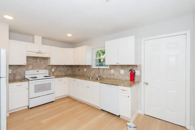 a kitchen with granite countertop white cabinets and white appliances