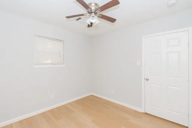 an empty room with a window and a ceiling fan
