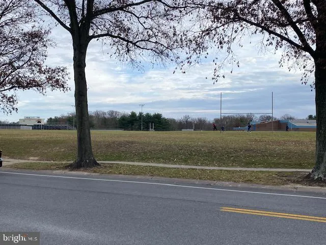 a view of a house with a yard and large trees