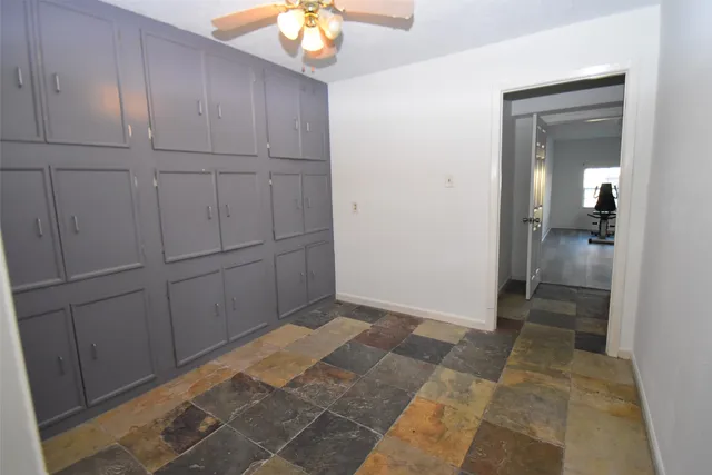 a view of an empty room with a ceiling fan and window
