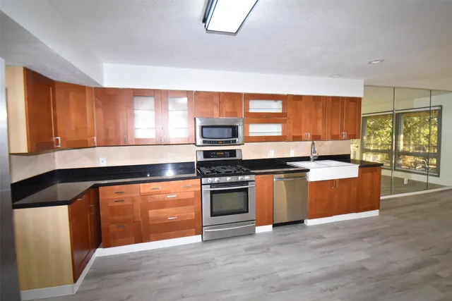 a kitchen with stainless steel appliances granite countertop a stove a sink and a microwave