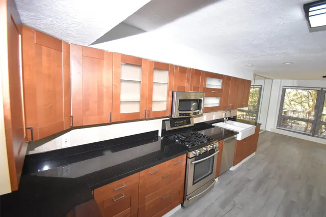 a kitchen with stainless steel appliances granite countertop a stove a sink and a microwave