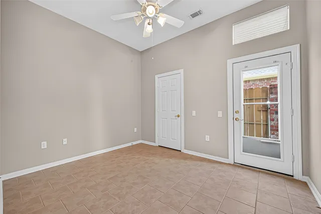 an empty room with a chandelier fan and windows