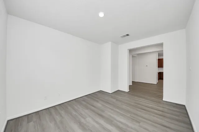 a view of an empty room with wooden floor and closet