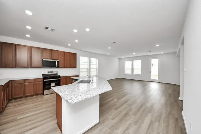 a large kitchen with stainless steel appliances granite countertop a large center island attached withe living room
