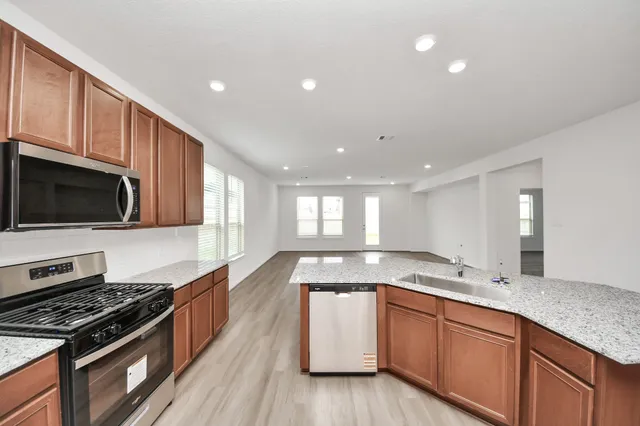 a large kitchen with stainless steel appliances granite countertop a stove a sink and a microwave