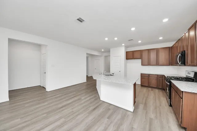 a large kitchen with stainless steel appliances a large counter top a stove and a wooden floors