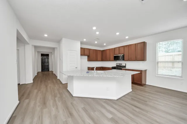 a view of kitchen with stainless steel appliances granite countertop a stove top oven a sink and a refrigerator