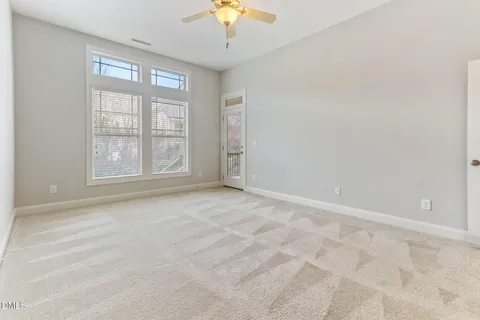 an empty room with wooden floor fireplace and windows