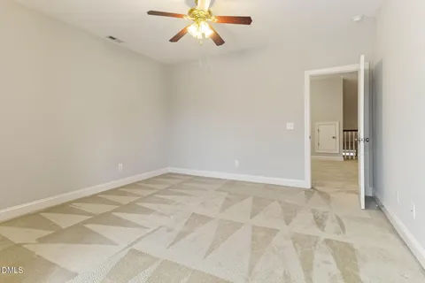 an empty room with chandelier fan and windows