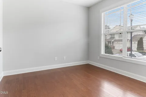 an empty room with wooden floor & windows
