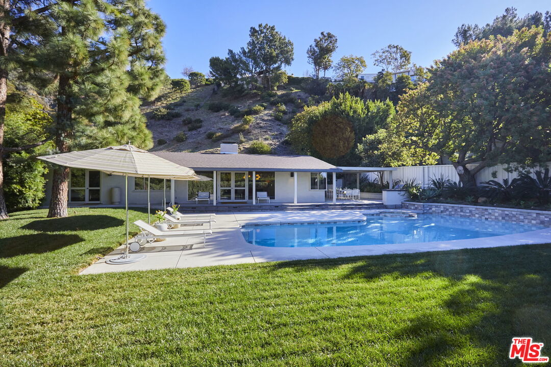9428 Lloydcrest Drive Beverly Hills, CA 90210 - Photo 29 of 36 a front view of a house with a yard table and chairs