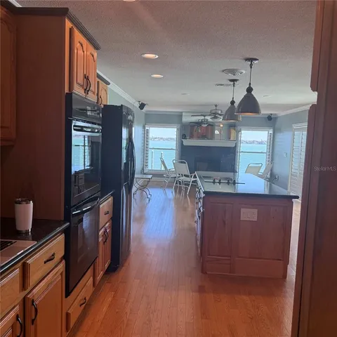 a kitchen with stainless steel appliances granite countertop a refrigerator a stove and a wooden floors