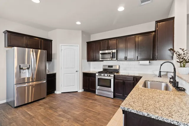 a kitchen with kitchen island granite countertop stainless steel appliances and wooden cabinets
