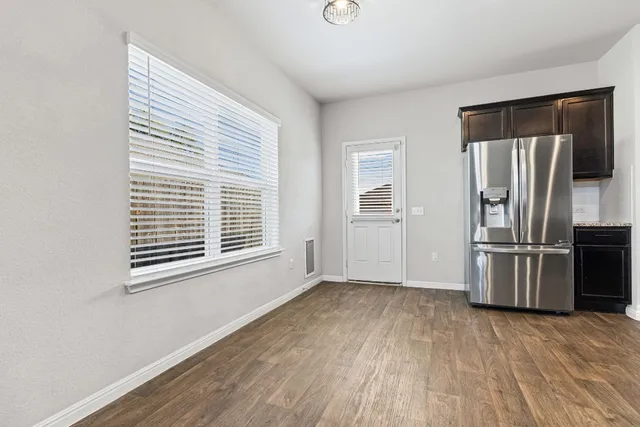 a view of empty room with wooden floor and window