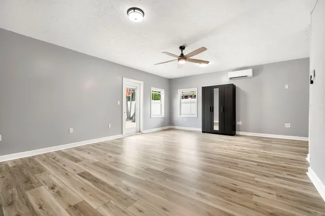 a view of an empty room with wooden floor and a ceiling fan