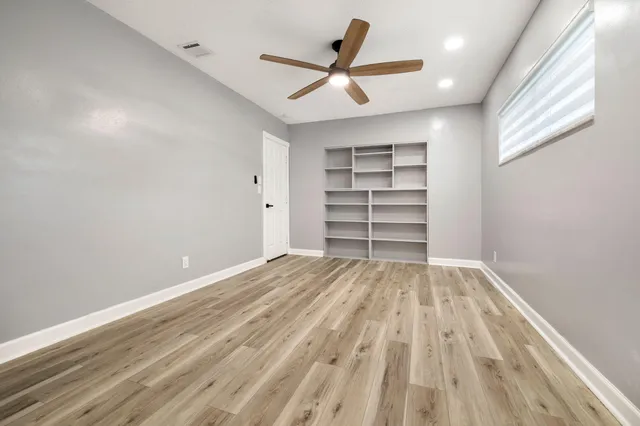 a view of a room with a ceiling fan and wooden floor