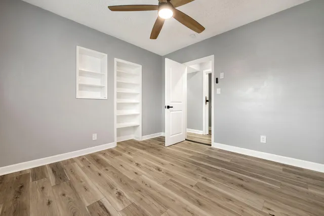 a view of an empty room with wooden floor and a window