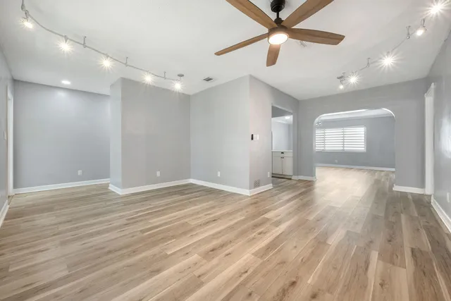 a view of empty room with wooden floor and fan