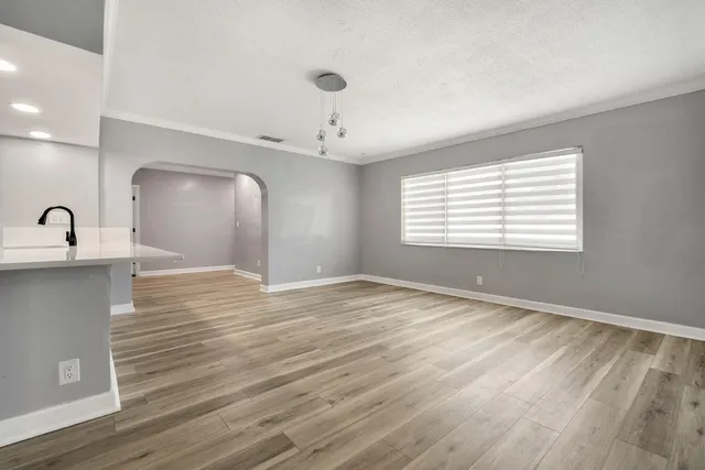 a view of an empty room with window and wooden floor