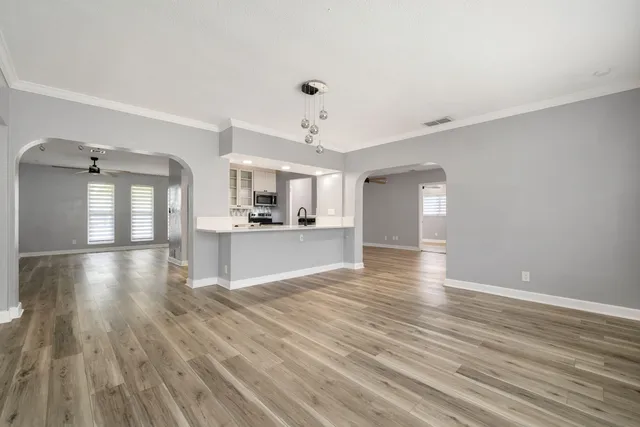 a view of a kitchen and an empty room with wooden floor and a kitchen