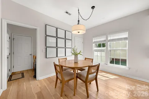 a dining room with wooden floor a chandelier a wooden table and chairs