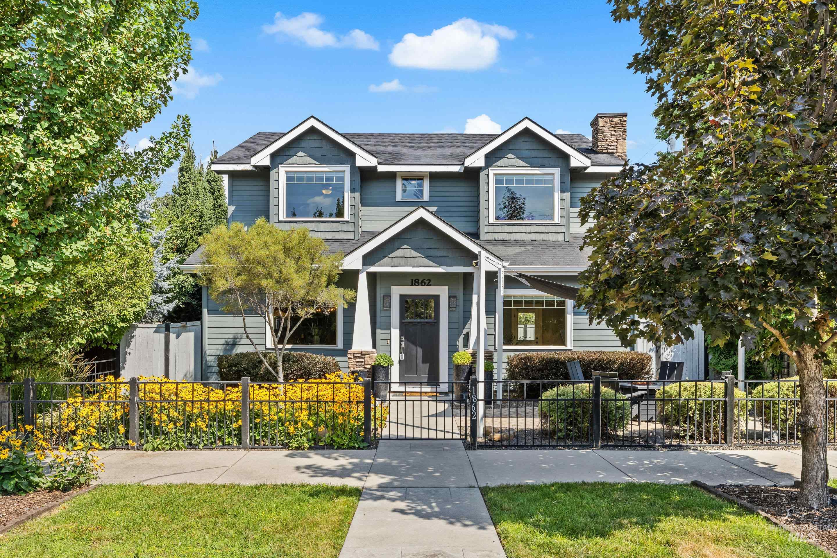 Two-story residence featuring dormer windows, a prominent front entry with a covered porch, and a stone-clad chimney